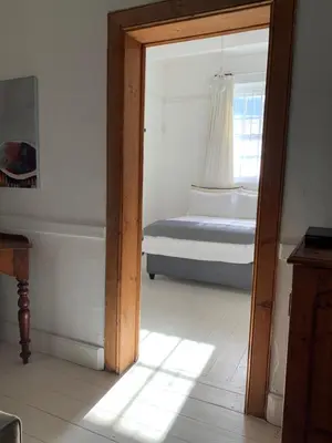 a room with a bedroom with a bed and a mirror at The Missions House in Hermanus