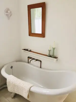 a white bath tub in a bathroom with a mirror at The Missions House in Hermanus