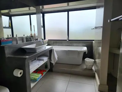 a bathroom with a tub and a sink and a bath tub at Moondust near the ocean, food and wine in Hermanus