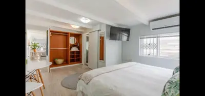 a bedroom with a bed and a table and a window at Antilles on Beach in Cape Town