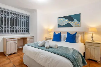 a bedroom with two beds with blue pillows at Ocean View 701 in Cape Town