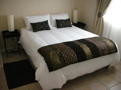 a bedroom with a large white bed with two pillows at On The Beach Front Sea Spray in Bloubergstrand