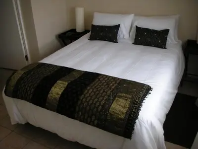 a large white bed with a blanket on it at On The Beach Front Sea Spray in Bloubergstrand