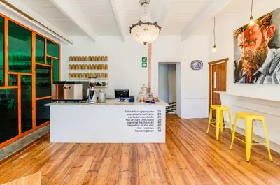 a kitchen with a counter and yellow stools at The Post House Hotel - no children under the age of 16yrs in Greyton