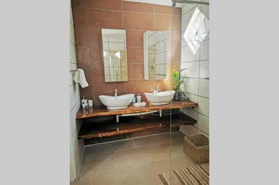 a bathroom with two sinks and two mirrors at The Blue Horizon House - Botrivier in Caledon
