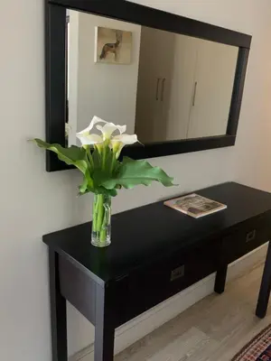 a vase of flowers on a table in front of a mirror at House Vos in Hermanus