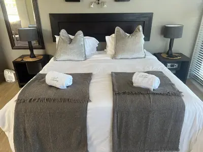a bedroom with a large bed with two towels on it at House Vos in Hermanus