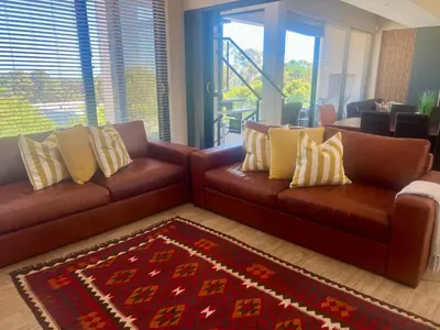 a living room with two brown leather couches and a rug at House Vos in Hermanus