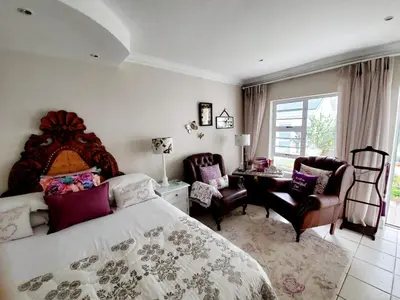 a bedroom with a bed and a desk and chairs at Gordon's Beach Lodge in Gordonʼs Bay