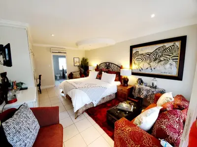 a large bedroom with a bed and a couch at Gordon's Beach Lodge in Gordonʼs Bay