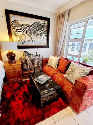 a living room with a couch and a painting of zebras at Gordon's Beach Lodge in Gordonʼs Bay