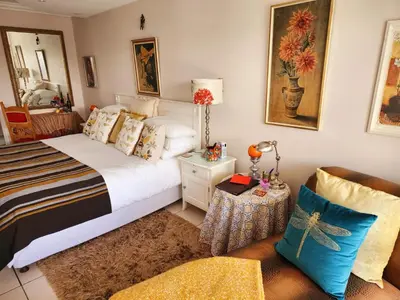 a bedroom with a bed and a table and a couch at Gordon's Beach Lodge in Gordonʼs Bay