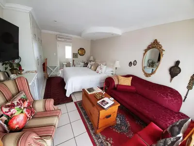 a bedroom with a bed and a living room with a couch at Gordon's Beach Lodge in Gordonʼs Bay