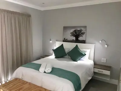 a bedroom with a bed with green and white pillows at Hermanus Guest Rooms in Hermanus