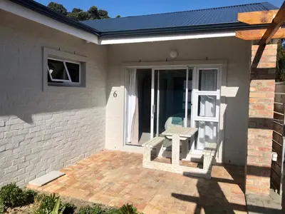 a patio with a table and a bench in front of a house at Hermanus Guest Rooms in Hermanus