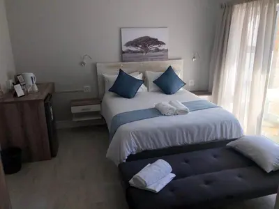 a bedroom with a large bed with towels on it at Hermanus Guest Rooms in Hermanus