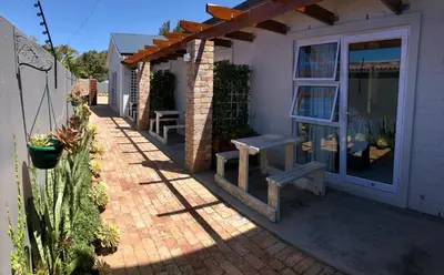 a patio with a bench and a window at Hermanus Guest Rooms in Hermanus