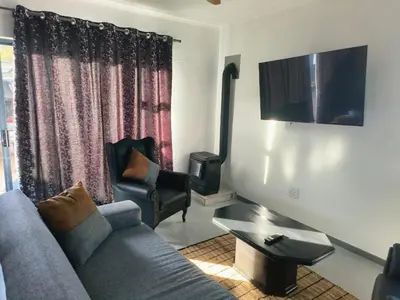 a living room with a couch and a chair at Sir James Self Catering in Cape Town