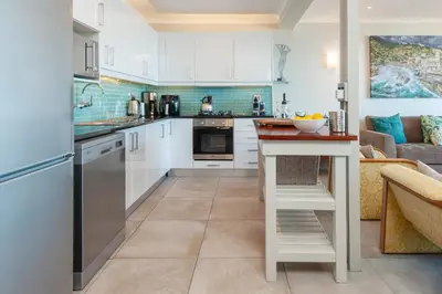 a kitchen with white cabinets and a counter at Walker Bay Luxury Seafront Apartment in Hermanus