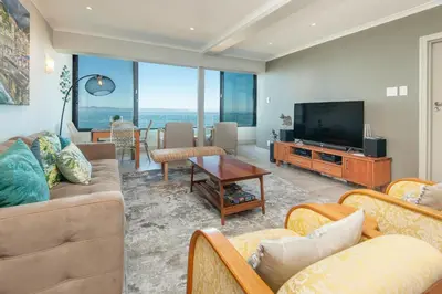 a living room with couches and a flat screen tv at Walker Bay Luxury Seafront Apartment in Hermanus