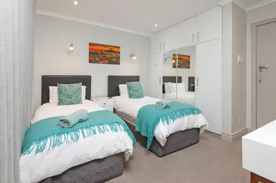 a bedroom with two beds and a mirror at Walker Bay Luxury Seafront Apartment in Hermanus