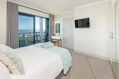 a bedroom with a bed and a view of the ocean at Walker Bay Luxury Seafront Apartment in Hermanus