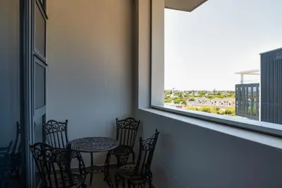 a table and chairs in a room with a window at Axis - Century City Self Catering Apartment in Cape Town