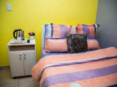 a bedroom with two beds and a yellow wall at Relaxing Guest Huse in the heart of Ndabeni in Cape Town