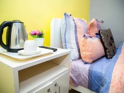a bed with a table with a coffee maker and pillows at Relaxing Guest Huse in the heart of Ndabeni in Cape Town