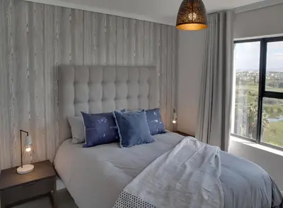 a bedroom with a large bed with blue pillows at Waters Edge Apartments in Cape Town