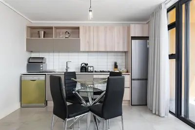 a kitchen with a glass table and black chairs at Waters Edge Apartments in Cape Town