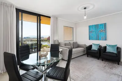 a living room with a couch and a table and chairs at Waters Edge Apartments in Cape Town