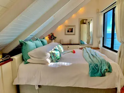 a bedroom with a bed with pillows and a window at 185 on BEACH Boutique Suites in Gordonʼs Bay