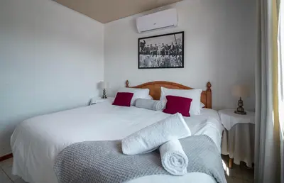 a bedroom with a large white bed with red pillows at Broadway Tygervalley House in Cape Town