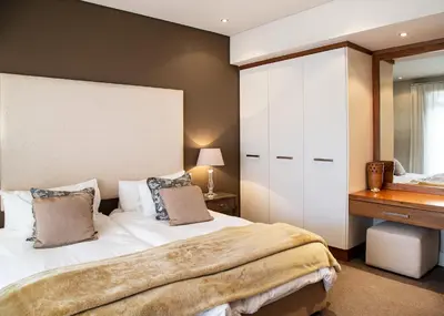 a bedroom with a large bed and a dresser at Marine Square Luxury Suites in Hermanus