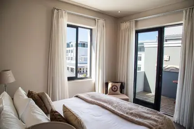 a bedroom with a bed and a large window at Marine Square Luxury Suites in Hermanus