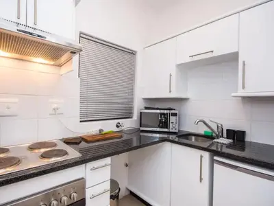 a white kitchen with a sink and a microwave at Church Street Luxury Apartments in Stellenbosch