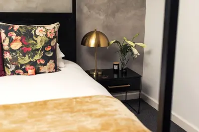 a bedroom with a bed and a lamp on a night stand at Franschhoek Maison du Cap in Franschhoek