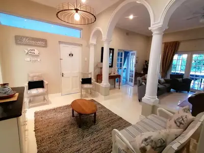 a living room with white furniture and an archway at Summer House in Hermanus