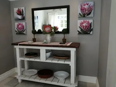 a bathroom with a vanity with a mirror and flowers at Summer House in Hermanus