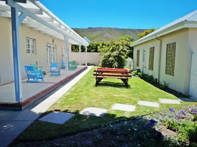 a wooden bench sitting in a yard next to a house at Summer House in Hermanus