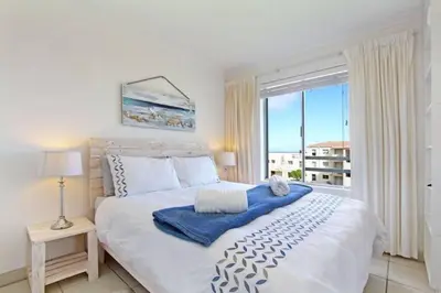 a bedroom with a large bed with a large window at Hermanus Beach Club - 106 - Apartment with a view in Hermanus