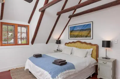 a bedroom with a bed and two lamps and a window at Die Rietdak - Reetdachhaus mit vier Schlafzimmern in Cape Town