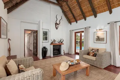 a living room with a couch and a table at Die Rietdak - Reetdachhaus mit vier Schlafzimmern in Cape Town