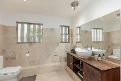 a bathroom with two sinks and a toilet at Die Rietdak - Reetdachhaus mit vier Schlafzimmern in Cape Town