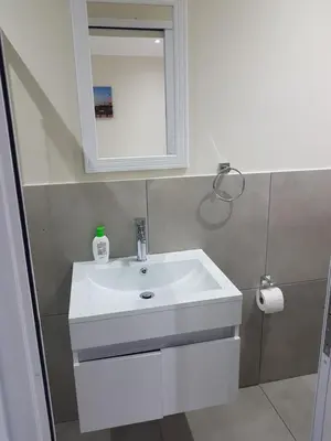 a bathroom with a white sink and a mirror at Sharon's House: Modern Self-Catering rooms in Cape Town
