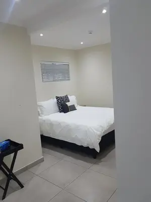 a bedroom with a bed in a white wall at Sharon's House: Modern Self-Catering rooms in Cape Town