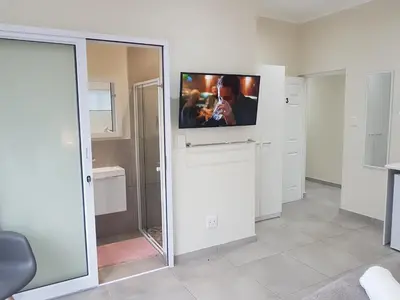 a room with a tv on a wall with a mirror at Sharon's House: Modern Self-Catering rooms in Cape Town