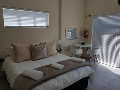 a bedroom with a large bed with a table and chairs at Sharon's House: Modern Self-Catering rooms in Cape Town