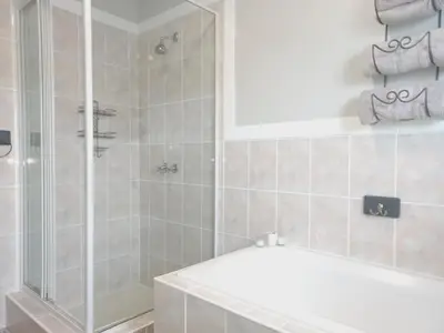 a bathroom with a shower and a white tub at Silverdunes - GardenView in Bettyʼs Bay